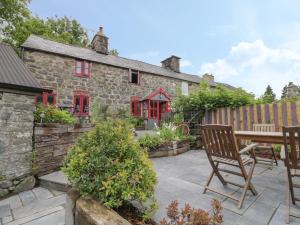 a patio with a table and chairs in front of a stone house at Bwthyn Dyfi in Machynlleth