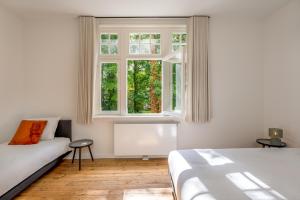 a white bedroom with a bed and a window at Maison Chartreuse in Bruges