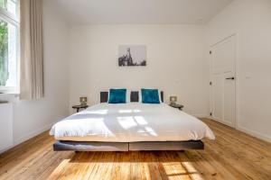 ein weißes Schlafzimmer mit einem großen Bett mit blauen Kissen in der Unterkunft Maison Chartreuse in Brügge