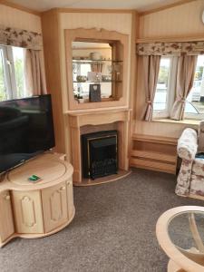 a living room with a television and a fireplace at Goldensands in Foryd