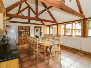 a kitchen and dining room with a wooden table and chairs at Beesoni Lodge in Castlemorton