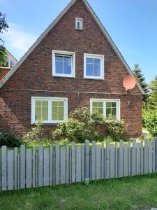 ein Backsteinhaus mit einem Zaun davor in der Unterkunft Steuerbord in Wangerland