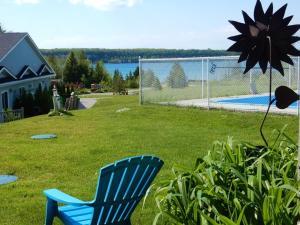 a blue chair sitting in the grass next to a fence at Waterview On The Bay in Wiarton