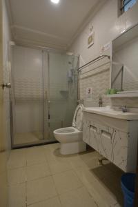 a bathroom with a shower and a toilet and a sink at Hemingway Cottage 海明威度假屋 in Semporna