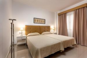 a bedroom with a large white bed and a window at Apartamentos Las Palmeras in Puerto de Mogán