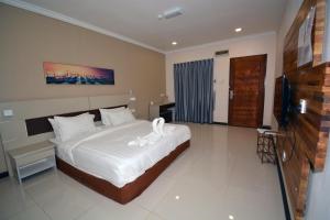 a bedroom with a bed with white sheets and a television at Hemingway Cottage 海明威度假屋 in Semporna