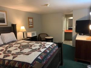 um quarto de hotel com uma cama e uma televisão de ecrã plano em St. Mary’s Motel 
