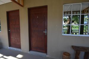 two wooden doors in a room with a window at Hemingway Cottage 海明威度假屋 in Semporna