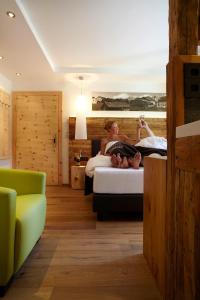 a woman sitting on a bed in a hotel room at Hotel am Römerweg in Fiss