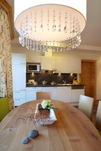 a kitchen with a wooden table with a chandelier at Hotel am Römerweg in Fiss