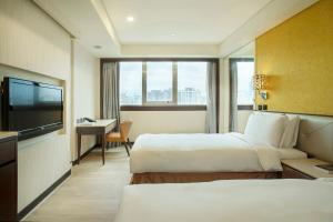 a hotel room with two beds and a flat screen tv at Hej Taipei Arena Hotel in Taipei