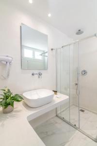 een witte badkamer met een wastafel en een douche bij Nama Boutique Hotel in Tinos Town