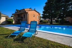 - deux chaises bleues installées à côté de la piscine dans l'établissement Prato Verde - Girasole, à San Felice del Benaco