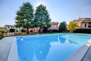 une grande piscine dans une cour avec deux arbres dans l'établissement Prato Verde - Girasole, à San Felice del Benaco