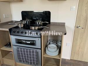 a kitchen with a stove with pots and pans on it at 8 berth caravan Presthaven Sands in Talacre