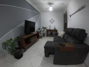 uma sala de estar com um sofá e uma televisão de ecrã plano em Beach House Itaguá Apartamento 1 - Em Ubatuba a 300m da orla mais charmosa, com excelente localização em Ubatuba