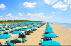 una playa llena de sombrillas azules en Marina Apartments en Marina di Grosseto