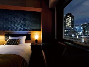 um quarto com uma cama e uma janela com um horizonte da cidade em DEL style Osaka Shin Umeda by Daiwa Roynet Hotel em Osaka