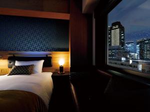 a bedroom with a bed and a window with a city skyline at DEL style Osaka Shin Umeda by Daiwa Roynet Hotel in Osaka