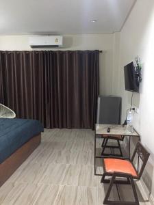 a bedroom with a bed and a desk with a television at Lampang Ngeng Na Home in Lampang