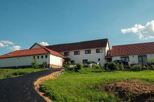a house with a road next to a grass field at Alsószuha Lovas Vendégház in Alsószuha