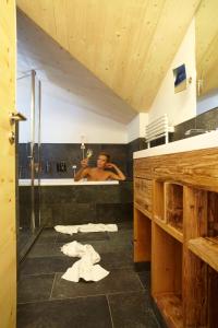 a man in a bathroom taking a bath in a tub at Hotel am Römerweg in Fiss