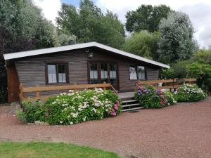 a small cabin with flowers in front of it at Chalet de vacances in Guisy
