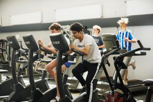 a group of young men exercising on treadles in a gym at Naturhytter in Kjellerup