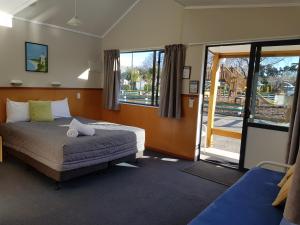 a bedroom with a bed and a sliding glass door at Timaru TOP 10 Holiday Park in Timaru