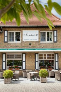 a building with tables and chairs in front of it at Logies Noorderlicht in Damme