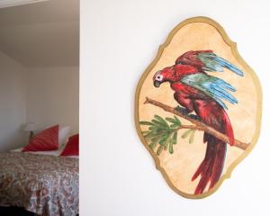 a painting of a red parrot sitting on a branch at Le Pavillon d'Arnajon in Le Puy-Sainte-Réparade