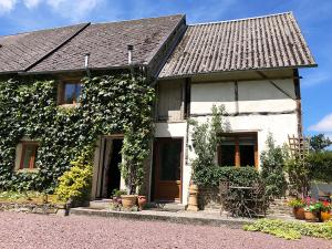 une maison blanche avec du lierre sur son côté dans l'établissement La Ferme Studio Apartments, à Condé-sur-Noireau