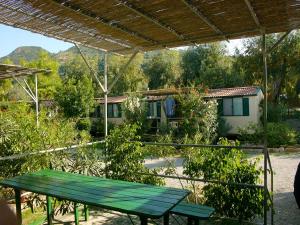 a green picnic table in front of a house at Camping Costa Ponente in Cefalù