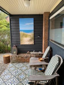 een afgeschermde veranda met 2 stoelen en een tafel bij Appartement Bos en Duin in Vogelenzang