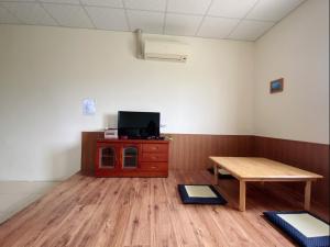 a room with a table and a tv and a wooden floor at Full power in Pa-wang-wei