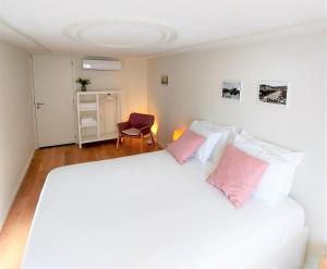 een slaapkamer met een groot wit bed met roze kussens bij Anjo33 Flats in Braga