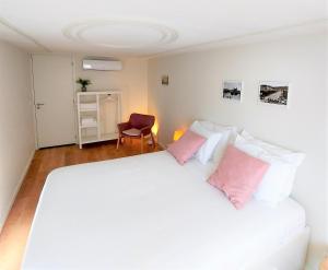 um quarto com uma grande cama branca com almofadas cor-de-rosa em Anjo33 Flats em Braga