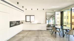cocina con paredes blancas, mesa y sillas en BnBIsrael apartments - Yavne Brillant en Tel Aviv