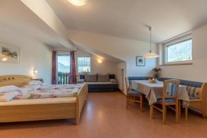 een slaapkamer met 2 bedden en een tafel en een bank bij Garni Dürrenstein in Schenna