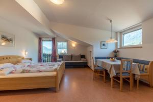 a bedroom with two beds and a table and a couch at Garni Dürrenstein in Schenna