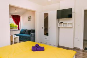 a room with a yellow bed with a purple object on it at Apartmani Markešić Ramsko jezero in Prozor