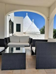 a patio with a couch and chairs and a building at Trullo Tranquillo Ostuni in Ostuni