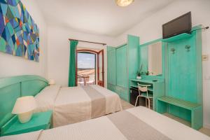 a bedroom with two beds and a desk and a television at Hotel Marinaro in Santa Teresa Gallura