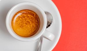 una tazza di caffè su un piatto con un cucchiaio di Hotel Marinaro a Santa Teresa di Gallura