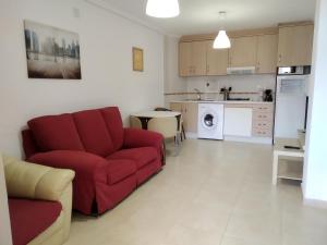 sala de estar con sofá rojo y cocina en Apartamento frente de la playa, en Torrevieja