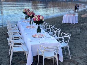 a long table with white chairs and flowers on a beach at Hotel Miramare & Spa in Sestri Levante