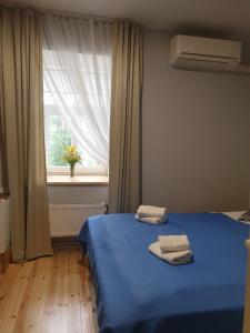 a bedroom with a blue bed with two towels on it at Sunset Hotel in Jūrmala