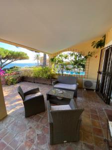 Un patio con sillas y mesas y vista al mar. en Villa Les Glycines, en Les Issambres