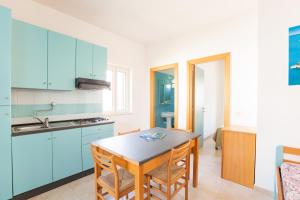 a kitchen with blue cabinets and a table and chairs at Villaggio Club In in Vieste