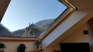 ein Dachfenster in einem Zimmer mit Blick auf ein Schloss in der Unterkunft viaDolceVita - Grüne Gästewohnung in Lana